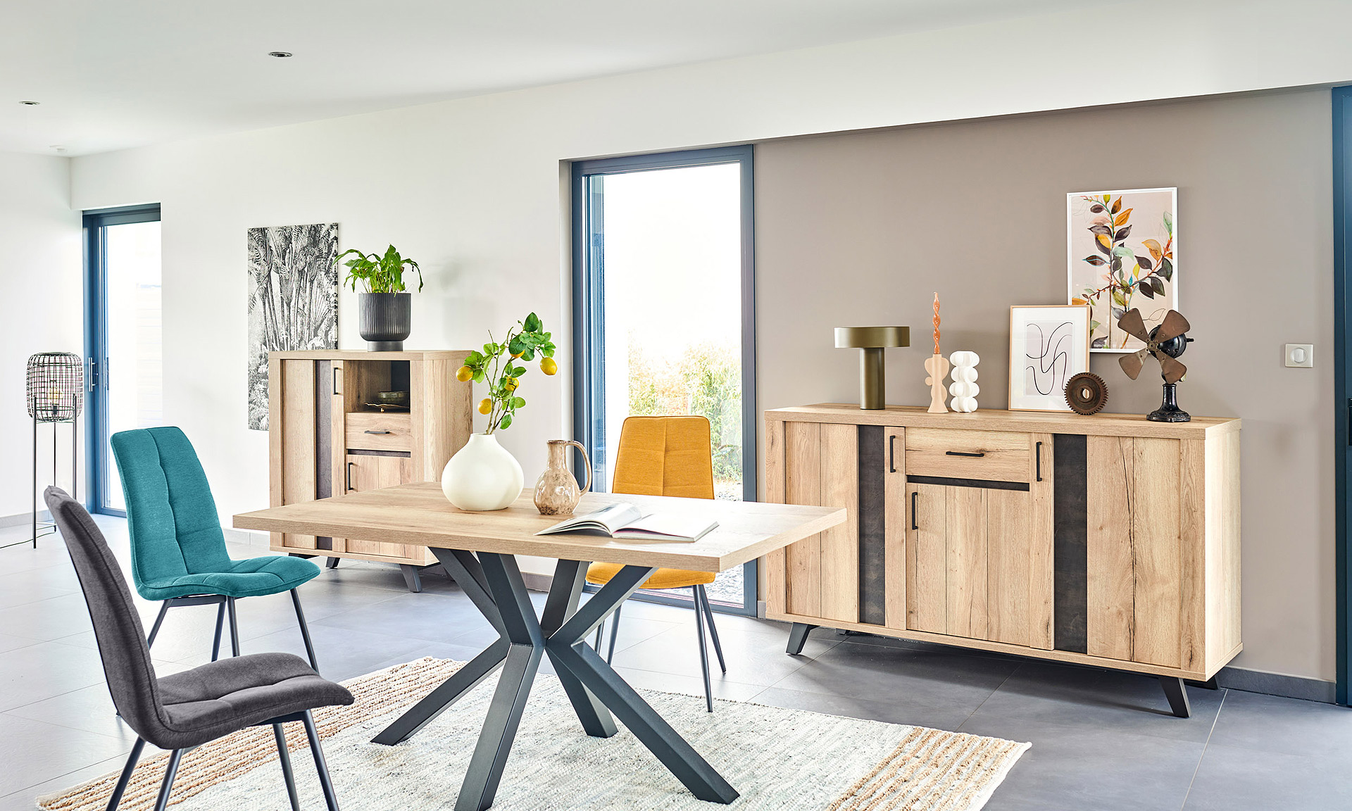 Photo d'une salle à manger avec une collection comprenant une enfilade, une table de repas, des chaises et un bibus. Les meubles présentent des finitions en chêne naturel style brut industriel et des piétements en métal noir.