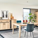 Photo d'une salle à manger avec une collection comprenant une enfilade, une table de repas, des chaises et un meuble de rangement. Les meubles présentent des finitions en chêne naturel style brut industriel et des piétements en métal noir.